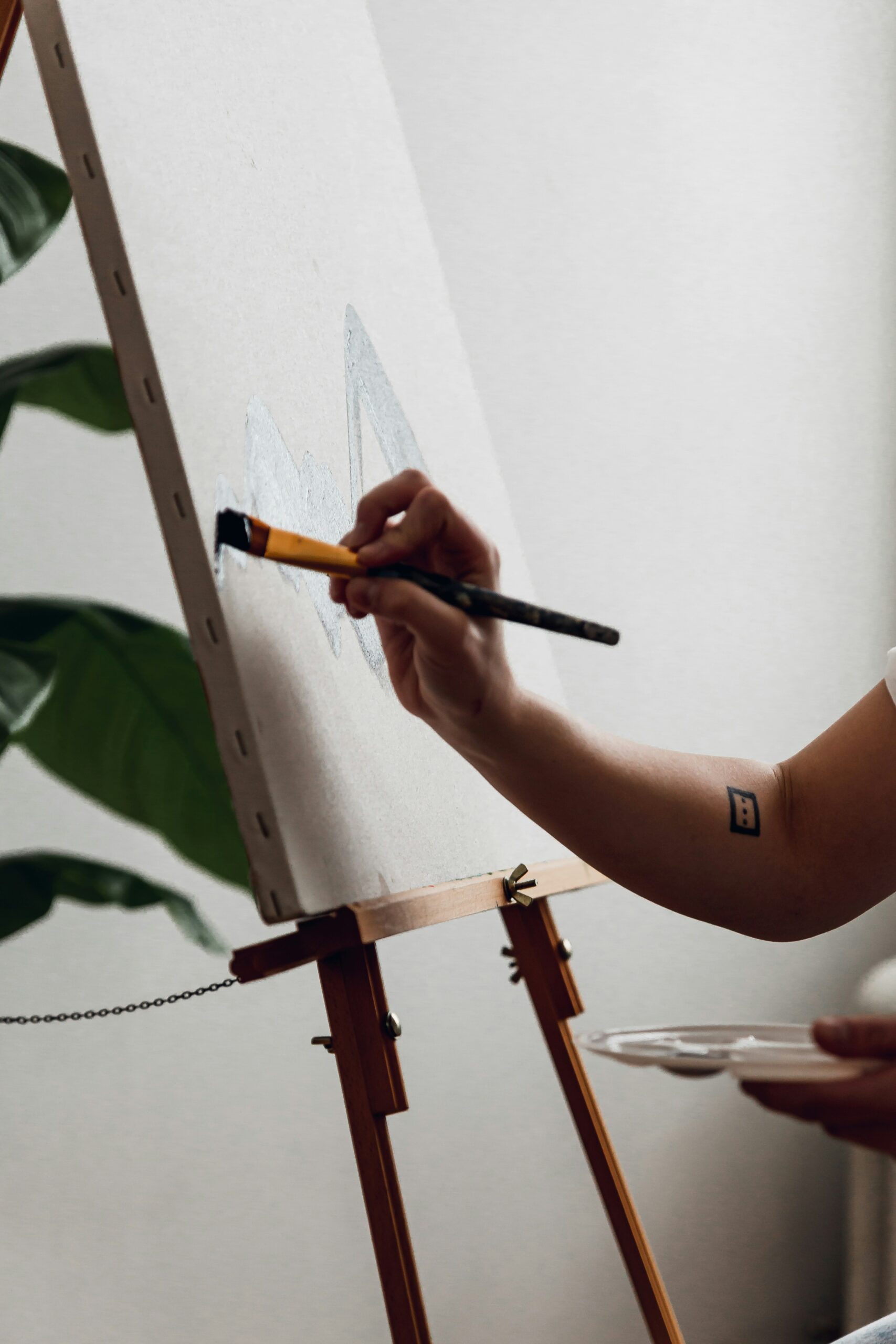 Hand painting a canvas, sketch in a studio. Photo by Sydney Riggs via Unsplash.
